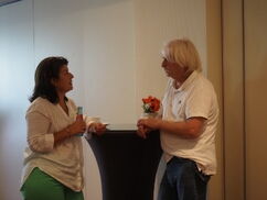 Zwei Personen stehen an einem Tisch und unterhalten sich