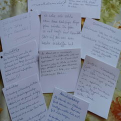 Beschriftete weiße Zettel liegen auf einem Tisch.