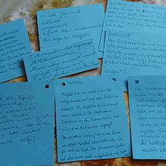 Beschriftete blaue Zettel liegen auf einem Tisch.