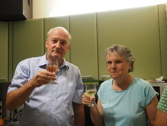 Ein Mann und eine Frau halten ein Weinglas in der Hand und schauen in die Kamera