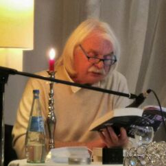 Ein Mann liest aus einem Buch, vor ihm steht ein Mikrophon