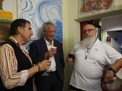 Drei Männer stehen mit Gläsern in den Händen nebeneinander und unterhalten sich