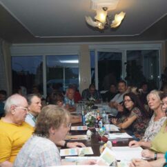 Viele Menschen sitzen in einem Raum an langen Tischen bei einem Workshop