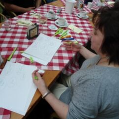 Eine Frau sitzt an einem Tisch und schreibt auf Papier