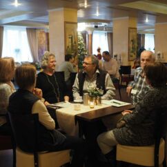 sechs Menschen sitzen in einem Restaurant an einem Tisch und unterhalten sich