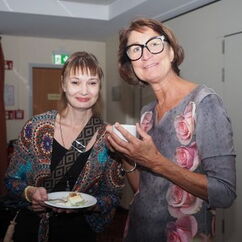 Zwei Frauen mit Kuchentellern in der Hand lächeln in die Kamera